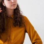 a woman in a yellow shirt is holding her hand to her ear