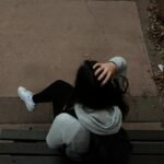 a person sitting on a bench on a sidewalk
